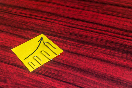 Paper clips attached by size on a yellow note with an arrow written on it.