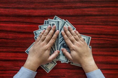 Hands grabbing money from a deskの写真素材