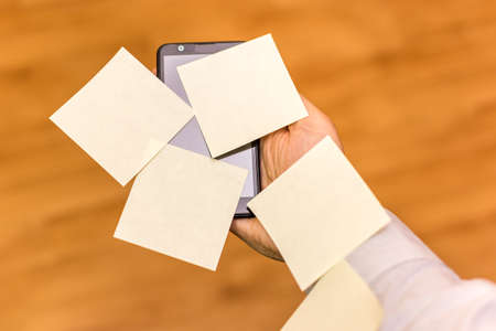 Human hand holdin a smarthpne covered with yellow sticky notesの写真素材