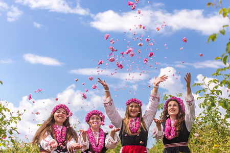 Four Bulgarian girls dressed in traditional clothing throwing rose in the air during the Annual Rose Festival in Kazanlak, Bulgariaの写真素材