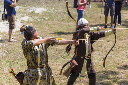 ASENVOGRAD, BULGARIA - JUNE 25, 2016 - Medieval fair in Asenovgrad recreating the life of Bulgarians during the Middle ages. Girl in a costume shooting arrows at a target.のeditorial素材