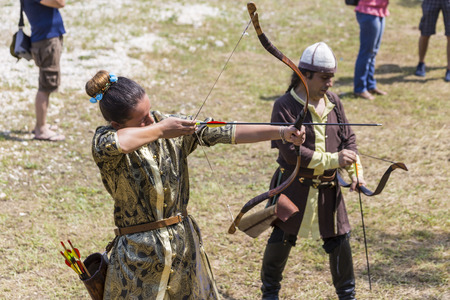 ASENVOGRAD, BULGARIA - JUNE 25, 2016 - Medieval fair in Asenovgrad recreating the life of Bulgarians during the Middle ages. Girl in a costume shooting arrows at a target.のeditorial素材