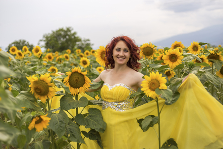Girl in a yellow dress feeling happy in a field of sunflowersの写真素材