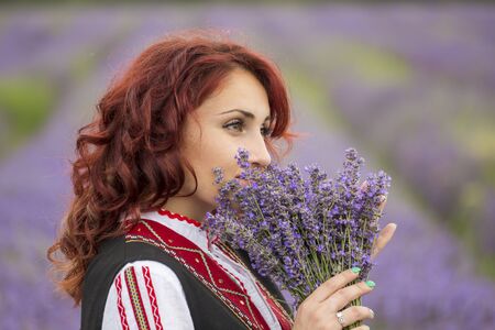 Woman dressed in traditional bulgarian dress called Nosia enjoying a walk in a lavender field.