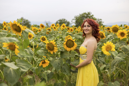 Girl in a yellow dress feeling happy in a field of sunflowersの写真素材