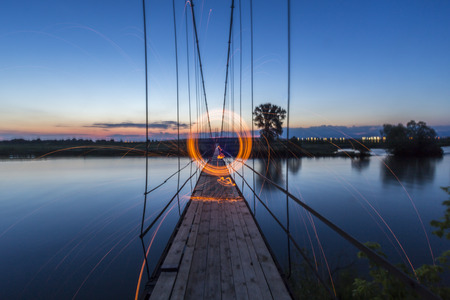 Steel wool circle on a suspension bridge looking like a portal trough space and timeの写真素材