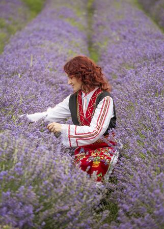Woman dressed in traditional bulgarian dress called Nosia enjoying a walk in a lavender field.の写真素材