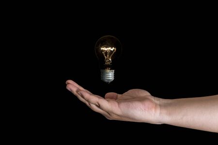 Human nad holding a lightbulb isolated on a black background. Having an idea concept.