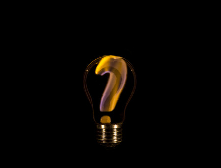 Question mark sign burning inside a light bulb isolated on black background. Problem solving concept.の写真素材