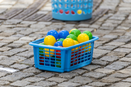 Small blue basket filled with colorful plastic ballsの写真素材