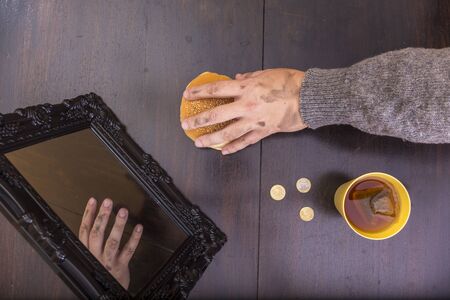 Human hand taking bread from a worn out table. Poverty concept. No reflection. Aerial view.の写真素材