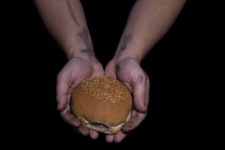 Poverty concept. Hands holding bread isolated on balck background.の写真素材