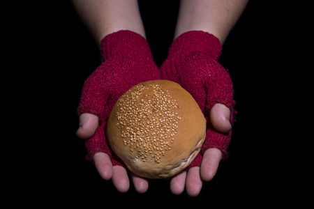 Poverty concept. Hands with dirty gloves holding bread isolated on balck background.の写真素材