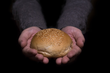 Poverty concept. Hands giving bread isolated on balck background.の写真素材