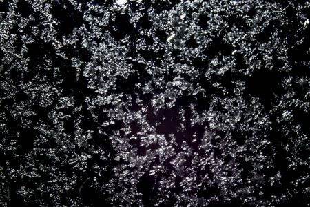 Snowflakes covered a glass window with black backgroundの写真素材