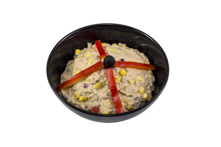 Black bowl with tuna salad in it. Decorated with red peppers and isolated on white.の写真素材