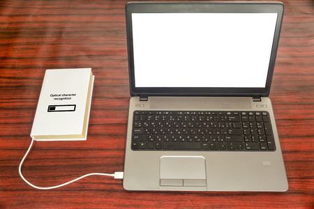 Book connected to a laptop through an USB cable. Optical character recognition loading bar.の写真素材