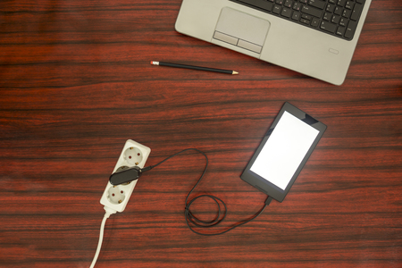 Tablet charging concept - Tablet connected to electric socket on a power strip through a cable and adapter.の写真素材