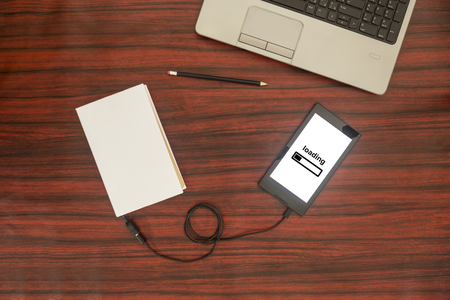Above view of a book connected to a tablet through an USB cable on a desk. Optical character recognition loading bar.の写真素材