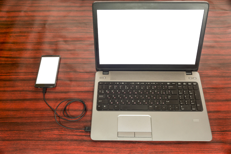 Data transfer concept. Cellphone and a laptop connected with USB cable.の写真素材