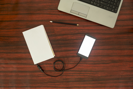 Data transfer concept. Cellphone and book connected with USB cable. Flat lay.の写真素材