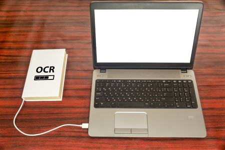 Book connected to a laptop through an USB cable. Optical character recognition loading bar.の写真素材