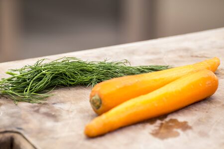 Dill and peeled carrot on a wooden boardの写真素材