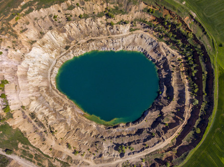 Aerial view of a crater created by mining machines and filled up with water creating an artificial lake.の写真素材