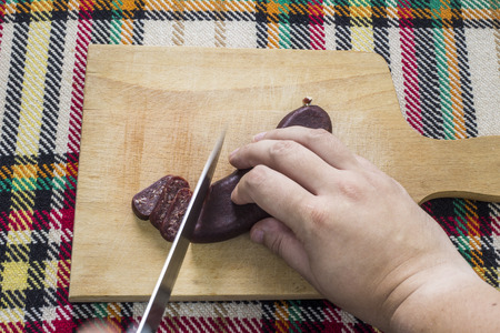 Cutting bulgarian traditional flat sausage called sudzhuk. First person point of view concept.の写真素材