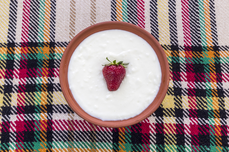 Beautiful and ripe strawberry in the middle of a bowl of yogurt.の写真素材