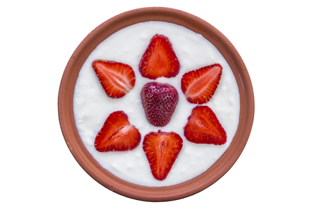 Strawberries sliced and beautifully arranged in a bowl of yogurt, isolated on white backgroundの写真素材