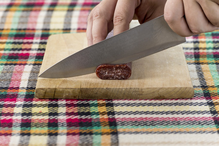 Cutting traditional Bulgarian flat sausage called lukanka