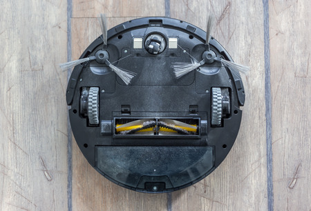 Robot vacuum cleaner upside down on the floor. Covered with dust after cleaning.の写真素材