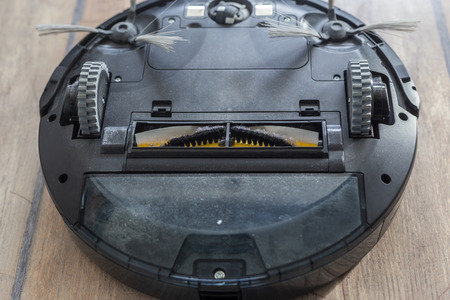 Robot vacuum cleaner upside down on the floor. Covered with dust after cleaning.の写真素材
