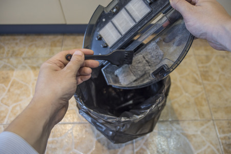 Person cleaning the dust bin of a robot vacuum cleander.の写真素材
