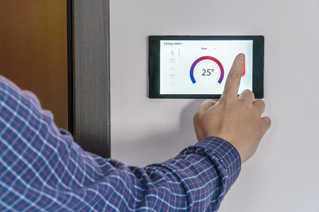 Smart home control and security concept. Person adjusting the temperature by pressing buttons on a...