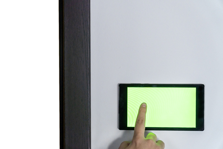 Smart home control and security concept. Device with blank screen hanging on a wall and person pressing button with his finger.の写真素材