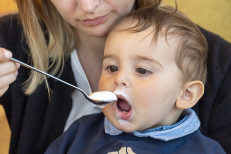 Mother feeding cute baby boy with some milk mashの写真素材