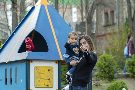 Baby boy pointing at the camera. Mother and son standing on outdoor playground.の写真素材
