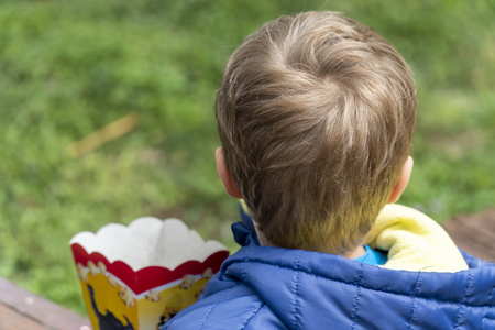 Yound boy eating popcorn at an outdoors parkの写真素材