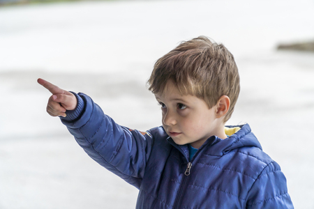 Young boy looking and pointing with his finger at somethingの写真素材