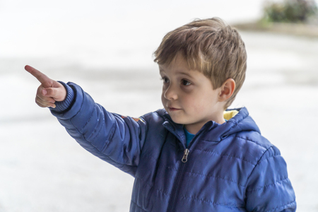 Young boy looking and pointing with his finger at somethingの写真素材