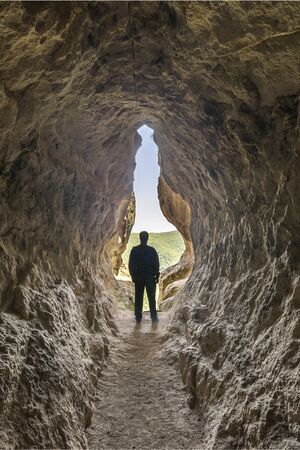 Human birth and light at the end of the tunnel concept. Man standing at the end of a small cave.