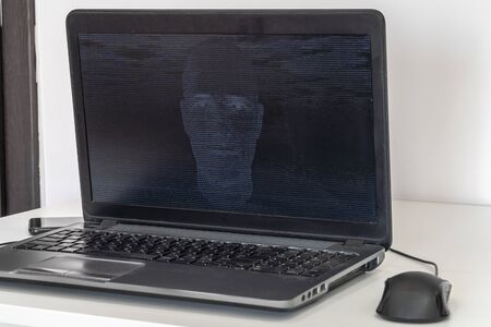 Developer coding on a laptop and creating a artificial intelligence software. Human like face made out of code appearing on the screen.の写真素材