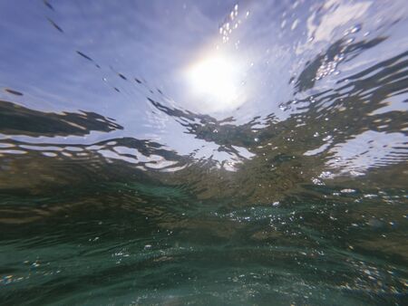 Underwater view of waives crashing. Beautiful sunlight coming through the water surface.