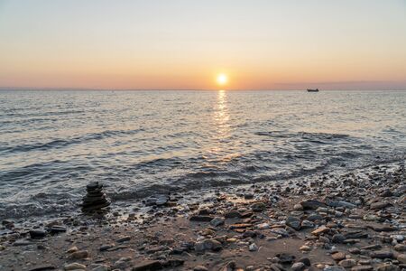 Stack of rock on the beach during sunset, with a boat in the background. Zen mood concept.の写真素材