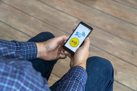 5g network danger concept. Man checking his smartphone with 5g network and warning sign displayed on...