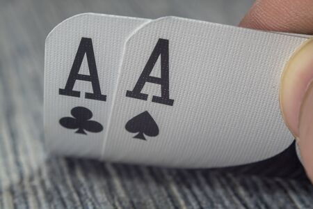 Low angle closeup view of a male hand picking up and showing cards from a casino tableの写真素材