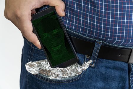 Man putting a smartphone in his pocket covered in aluminum foil with AI bot on the screenの写真素材