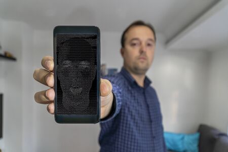 Man shwing smartphone to the camera with AI bot face on the screenの写真素材